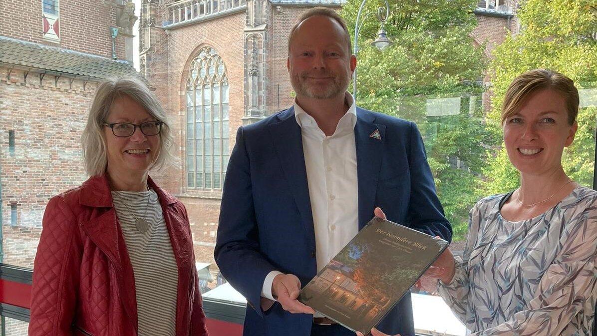 Steffi Koop und Christina Martens übergeben Buch mit Fotos aus Gera an den Beigeordneten des Bürgermeisters von Arnheim, Maurits van de Geijn